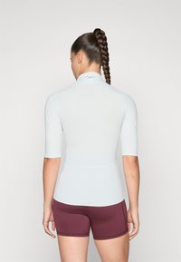 Lyseblå, kortermet aktiv topp med ståkrage, parret med mørkerøde shorts. Glatt tekstur, tettsittende design, minimalistisk stil.