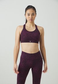 Σπορ σουτιέν και κολάν σε σκούρο μοβ με διακριτικό λεοπάρ σχέδιο. Λείο υφασμά και κομψή σχεδίαση, με φαρδιές τιράντες για στήριξη.