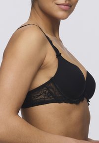 Black bra with lace trim featuring a seamless, smooth cup design, adjustable straps, and bow accent on the strap, showcasing a delicate texture.
