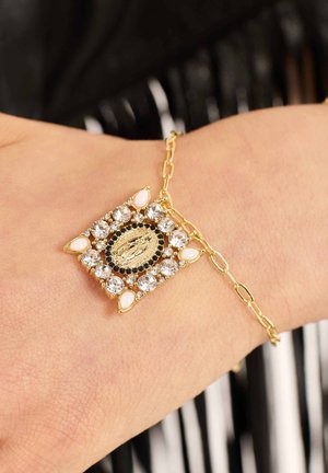 Goldarmband mit einem rechteckigen Edelsteinanhänger, der mit klaren und schwarzen Steinen sowie ovalen weißen Akzenten verziert ist, befestigt an einem Gliederband.