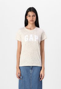 Trumpas rankovėmis, smėlio spalvos T-marškiniai su leopardų raštu ir baltu "GAP" logotipu priekyje. Lygus audinys ir standartinis pjūvis, derinamas su džinsiniu sijonu.