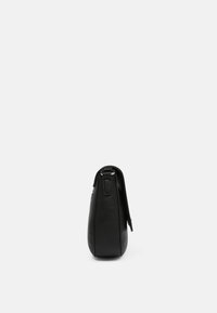 Schwarze Lederhandtasche mit strukturiertem Finish, herausragendem Seitenprofil, sicherem Tragegurt und minimalistischen Designelementen.