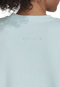 Sweat-shirt en coton bleu clair avec col ras du cou côtelé et texte en relief "ALL SZN" sur le haut du dos. Texture lisse, design décontracté.