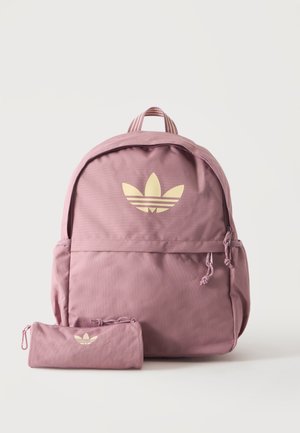 Sac à dos Adidas rose et trousse assortie avec logo trèfle beige sur un fond clair et uni.