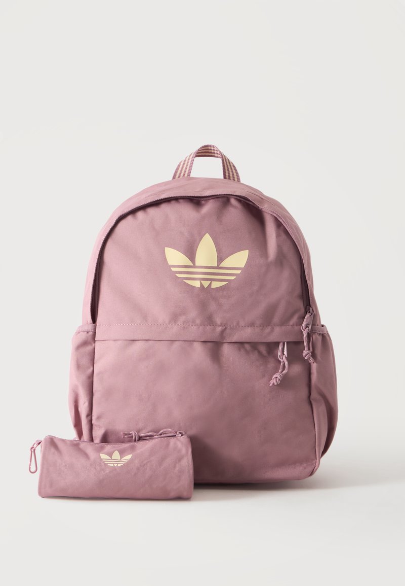 Ροζ σακίδιο Adidas και ασορτί κασετίνα με μπεζ λογότυπο τριφύλλι σε απλό ανοιχτό φόντο.