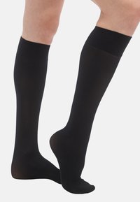 Sorte knæstrømper lavet af glat, elastisk materiale med ensfarvet mønster og blød, elastisk kant for en sikker pasform.