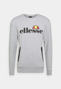 Sudadera gris claro con el logo "ellesse" en negro y emblema amarillo-rojo en el pecho, con dos bolsillos verticales negros con cremallera.