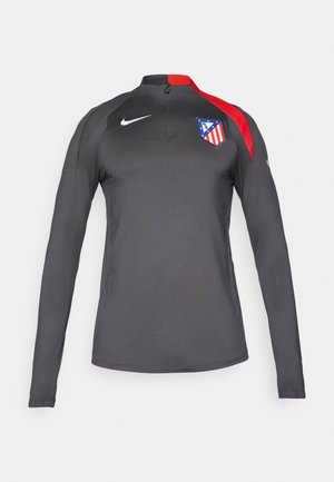 Long-sleeve athletic top in dark gray with red accents and a zip mock neck. Features team logo on left chest. Made of flexible, breathable fabric.