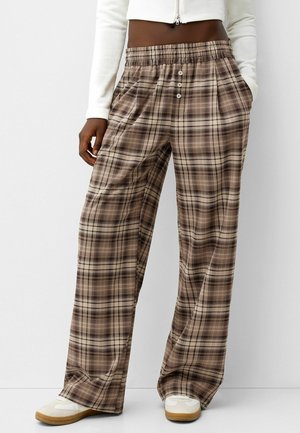 Rutet vide bukser i brunt og beige, med snørre i taljen, frontlommer og tre knapper i taljen.