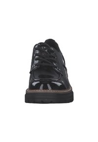 Scarpa in vernice nera con punta arrotondata, design con lacci e suola marrone a contrasto. Presenta una superficie liscia e dettagli di cucitura minimali.