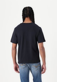 Marineblå T-shirt med klassisk rund halsudskæring, korte ærmer og en afslappet pasform. Sammen med lyseblå jeans med et diskret baglomme-design.