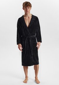 Sort luksuriøs badekåbe med sjalskrave, bånd foran og to forlommer. Blød tekstur, knælangt design og lange ærmer.