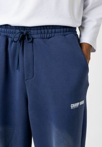Navyblauwe joggers van een zachte katoenmix, voorzien van een elastische tailleband met een trekkoord en een bedrukte logo op de dij.