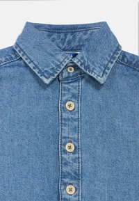 Τζιν πουκάμισο με κλασικό γιακά, ανοιχτό μπλε χρώμα, με κουμπώματα στο μπροστινό μέρος με μπεζ κουμπιά και υφασμάτινη υφή.