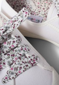 Sneakers in tela con esterno bianco, caratterizzati da lacci con motivo floreale in rosa e verde, e foderati con tessuto testurizzato.