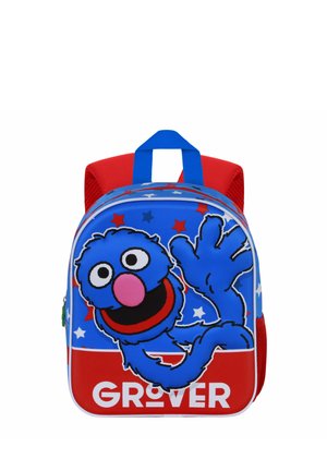 Sac à dos bleu et rouge avec un personnage de dessin animé, un dos texturé, des motifs d'étoiles, et une fermeture éclair à l'avant. Comprend une poignée supérieure.