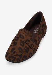 Mocasines de ante marrón con un patrón de leopardo, que cuentan con una suela plana, punta redondeada y acentos de costura en el empeine.