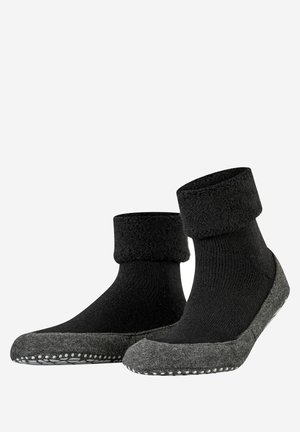 Black soft socks with a grey, textured sole and a fluffy cuff. The sole features white dot accents for traction.