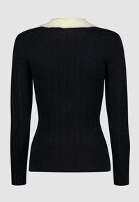 Maglione nero lavorato a maglia con texture a coste, maniche lunghe e colletto chiaro a contrasto con piccole decorazioni.
