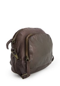 Hnědá kožená crossbody taška s kulatým tvarem, se dvěma zlatými zipy, nastavitelným popruhem a texturovaným povrchem.