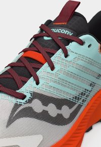 Αθλητικό παπούτσι με επάνω μέρος από διχτυωτό υλικό σε τιρκουάζ και γκρι, κόκκινα και μαύρα κορδόνια, πορτοκαλί λεπτομέρειες και υφή στη μαύρη γλώσσα με το λογότυπο Saucony.