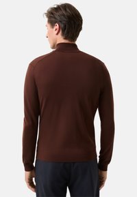 Brauner, langärmeliger Pullover mit hohem Kragen und gerippten Bündchen, aus strukturiertem Strickstoff gefertigt. Enthält eine seitliche Nahtakzentuierung mit Hardware.