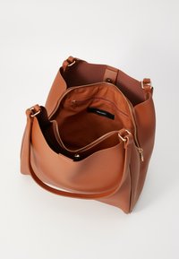 Sac à main en cuir marron avec une texture lisse, forme arrondie, fermeture par zip en haut et poche zippée intérieure. Sangle d'épaule réglable incluse.