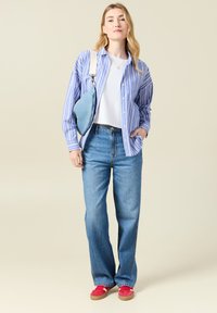 Sinivalkoraidalliset nappipaidat, valkoinen t-paita, löysät siniset farkut ja punaiset lenkkarit. Ristiin kulkeva laukku denimkangasta.