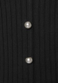 Schwarzer gerippter Stoff mit zwei glänzenden Perlenknöpfen als vertikale Akzente, die Textur und Designelemente hervorheben.