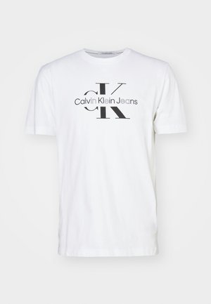 White cotton t-shirt with a crew neck, featuring a black "Calvin Klein Jeans" logo and monogram design printed on the front.