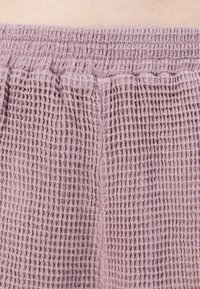 Shorts en tricot gaufré en doux tissu mauve, avec une taille élastique et un motif texturé pour une meilleure respirabilité et un confort optimal.