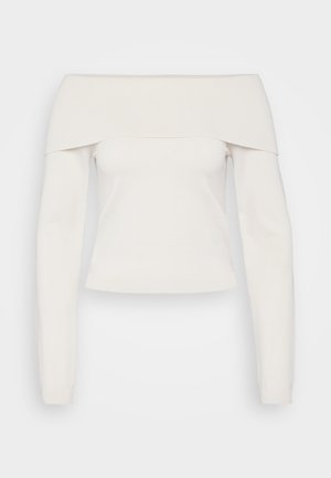 Kreklis ar atklātiem pleciem un garām piedurknēm, izgatavots no mīksta baltā adījuma, ar ribotu dekoltē un pieguļošu siluetu, ar gludu faktūru un minimāliem šuvēm.