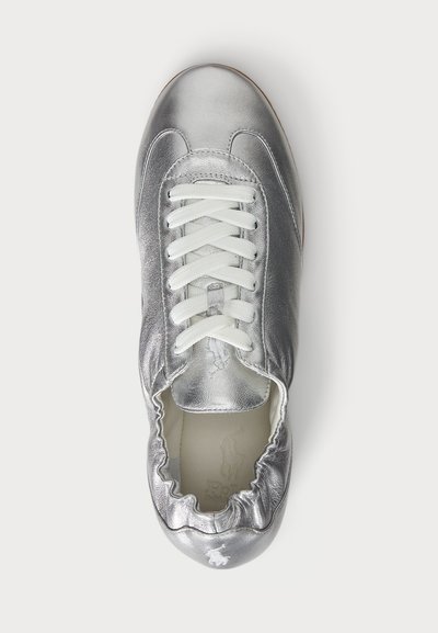 Sömlös silverfärgad sneaker med vita snören, rund form, elastiska kanter och en subtil präglad logotyp på innersulan. Slät textur.