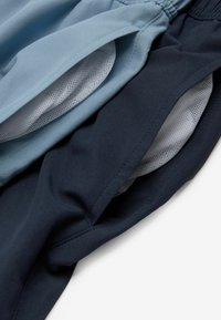 Shorts din țesături de albastru deschis și navy închis, având buzunare din plasă, talie elastică și textură netedă. Vedere de aproape a stratificării.
