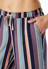 Pruhované pohodlné kalhoty s elastickým pasem a šňůrkou. Barvy zahrnují námořnickou modř, broskvovou, světle modrou a levandulovou, s jemnou texturou.