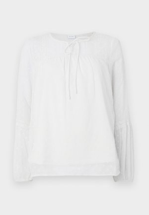Hvid langærmet bluse med blonde detaljer, rund halsudskæring, samlet bærestykke og teksturerede prikker på et glat stof.