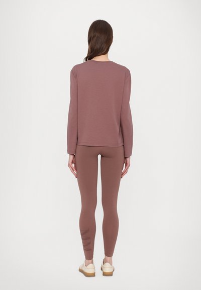 Mauve long-sleeve top paired with matching leggings, both in soft fabric. Leggings feature a logo print along the side. Simple, fitted design.