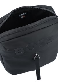 Sac à dos en nylon noir avec logo "BOSS" en relief, fermeture éclair et un design épuré. Doté d'un accent en métal argenté.