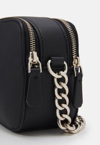 Borsa a tracolla in pelle nera con doppia cerniera, ferrature argentate e tracolla a catena spessa. Texture liscia con forma rettangolare arrotondata.