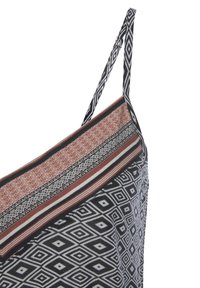 Schwarz-weißer Stoff mit einem diagonal gestreiften oberen Bereich in Rot und Beige. Verfügt über gewebte Träger und eine strukturierte Oberfläche.