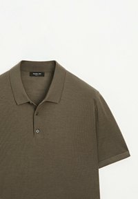 Olivově zelená polo košile vyrobená z hladkého pleteného materiálu. Má tradiční límec, dvě knoflíky na zapínání a krátké rukávy.