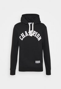 Černá mikina s kapucí a bílými šňůrkami, text "CHAMPION" prohnutý na přední straně a malá obdélníková nálepka blízko dolního lemu.