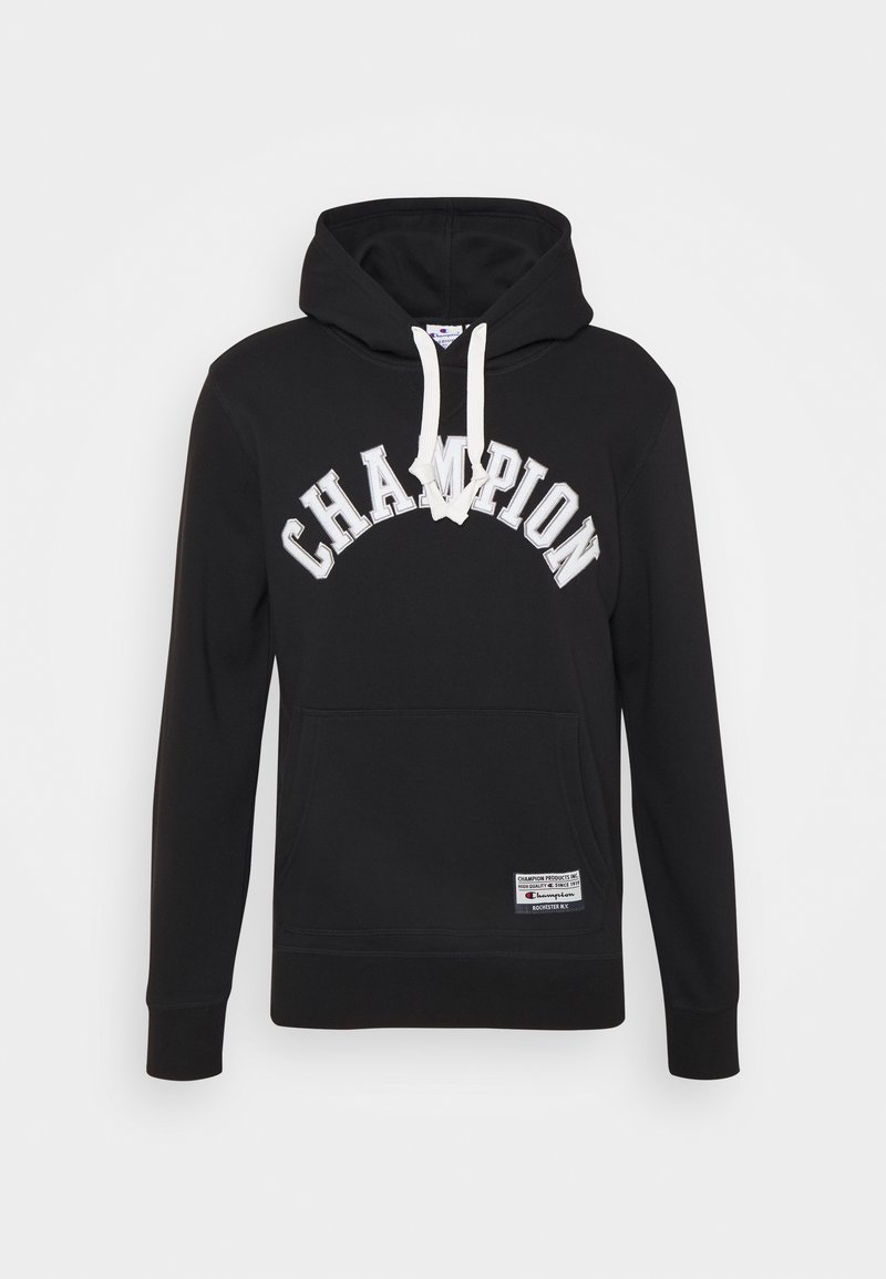 Černá mikina s kapucí a bílými šňůrkami, text "CHAMPION" prohnutý na přední straně a malá obdélníková nálepka blízko dolního lemu.