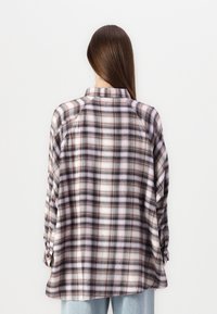 Ruudullinen flanellipaita, jossa on pehmeä ja harjattu pinta pinkin, purple ja ruskean sävyissä, rento istuvuus ja käännetyt hihat.