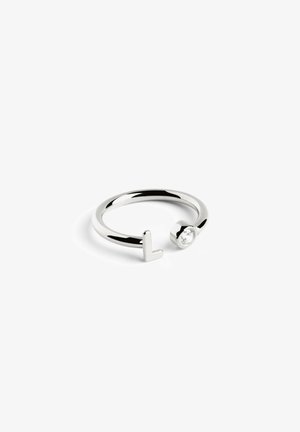 Bague ouverte en argent fin présentant un design plat en "L" d'un côté et une pierre ronde transparente de l'autre, offrant un look moderne et épuré.