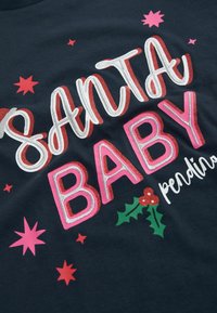 Tamsus marškinėliai su užrašu "SANTA BABY" ryškiais blizgučiais, apsuptais rožinių ir raudonų žvaigždžių bei pūslių lapų su raudonomis uogomis.