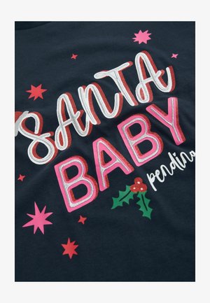 Tengerészkék t-shirt, amelyen a "SANTA BABY" felirat nagy, csillogó betűkkel szerepel, körülötte rózsaszín és piros csillagok, valamint piros bogyós hollólevelek.
