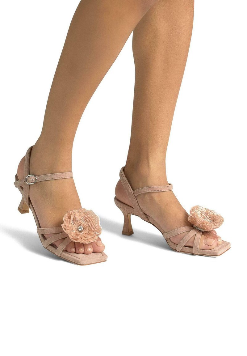 Rosa High-Heels-Sandalen mit quadratischer Spitze, die mehrere Riemen und eine Blumenverzierung aufweisen. Strukturiertes Material mit einem subtilen Glanz.