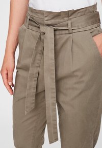 Pantalons en tissu vert olive atténué avec une large taille, des plis à l'avant et un détail de ceinture nouée. Texture lisse avec une coupe décontractée.