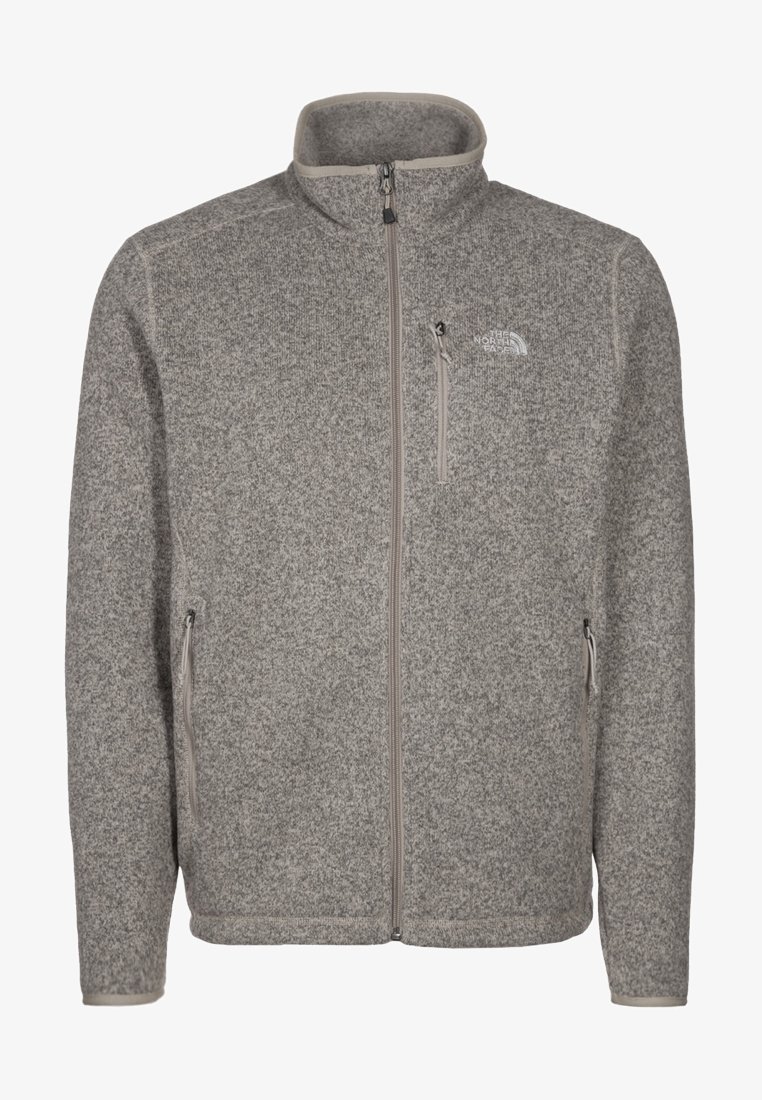 Chaqueta de forro polar gris con cuello alto, cremallera frontal, dos bolsillos laterales y un bolsillo en el pecho con cremallera. Presenta una tela texturizada y un logo sutil.